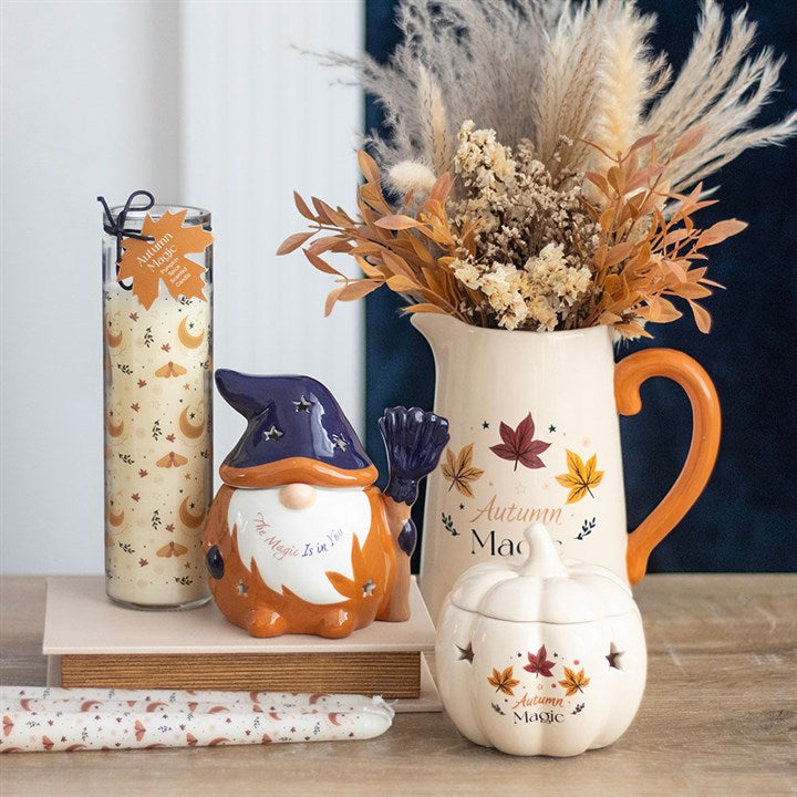 Autumn-themed decor items including a gnome, pitcher, and pumpkin on a wooden surface.