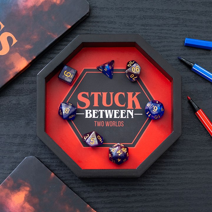 Hexagonal tray with dice and 'Stuck Between Two Worlds' text on a dark surface