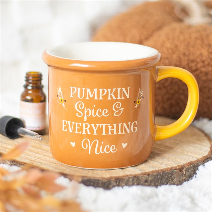 Orange mug with 'Pumpkin Spice & Everything Nice' text on a wooden surface with a bottle and spoon in the background.