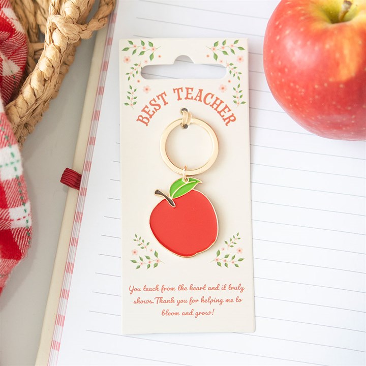 Keychain with 'Best Teacher' message on a card, next to an apple and a basket.