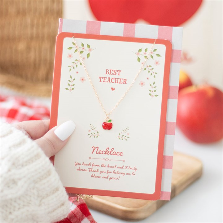 Necklace packaging with 'Best Teacher' text and an apple design, held by a hand.