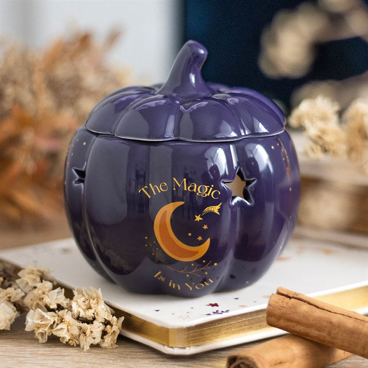 Purple pumpkin-shaped container with 'The Magic is in You' text on a wooden surface with dried flowers and cinnamon sticks.