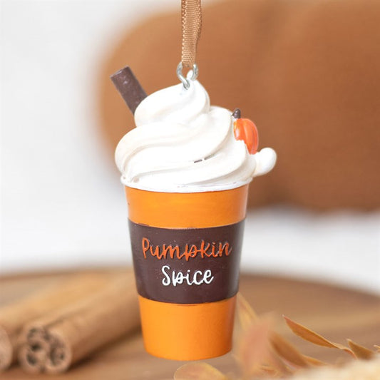 Pumpkin spice latte ornament with whipped cream and cinnamon sticks on a blurred background