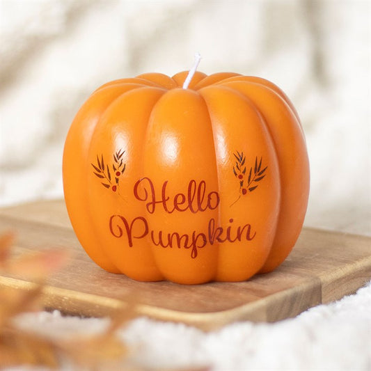 Pumpkin-shaped candle with 'Hello Pumpkin' text on a wooden surface