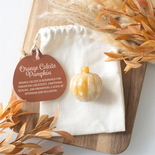 Decorative pumpkin with orange calcite on a white cloth, surrounded by dried leaves.