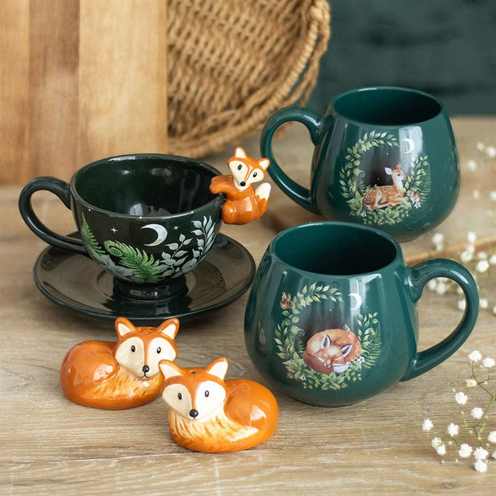 Set of green mugs with fox designs on a wooden surface