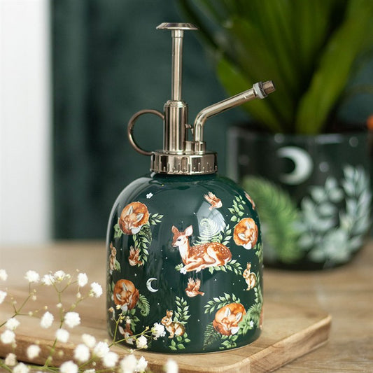 Decorative green spray bottle with animal and floral design on a wooden surface.