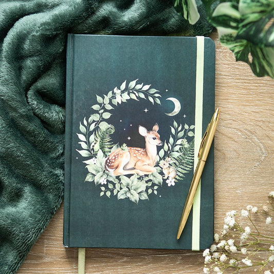 Notebook with deer illustration on a wooden surface with a pen and green fabric.