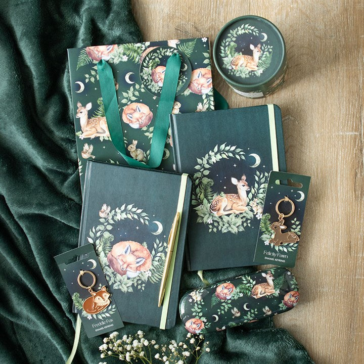 Collection of green-themed products including notebooks, bags, and keychains with nature and animal designs on a wooden surface.