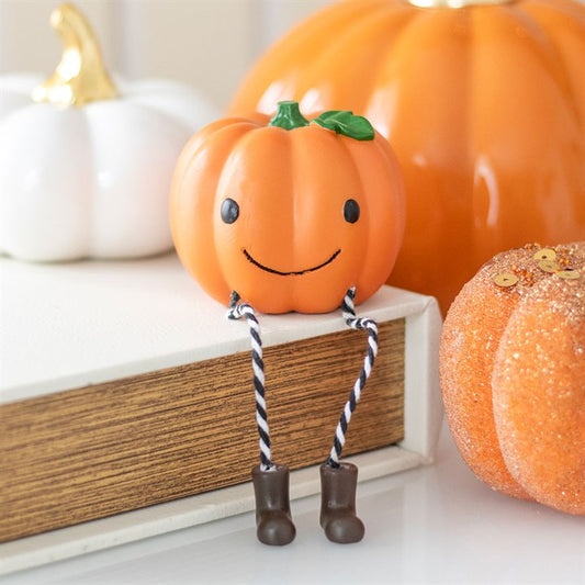 Pumpkin-shaped decorative item with a face and legs, surrounded by real pumpkins.